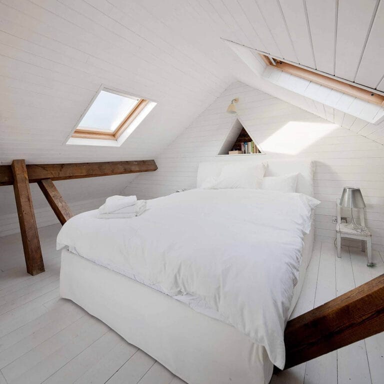 Luxury loft conversion bedroom featuring exposed wooden beams in Wanstead